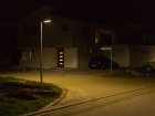 Mit moderner LED-Leuchte optimal ausgeleuchtete Stra&szlig;e und Gehweg. Die Hausfassade wird kaum erhellt.